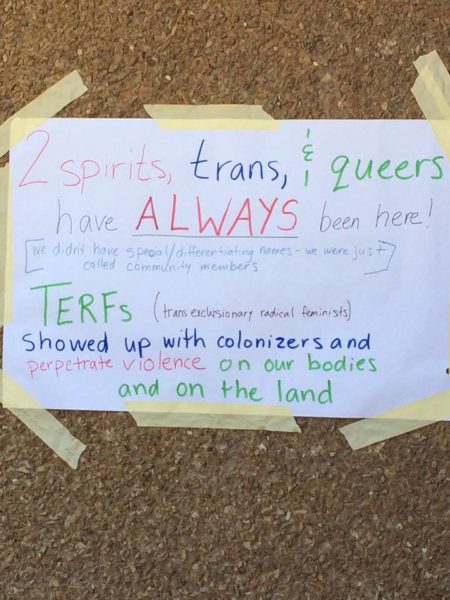 Varying colored markers on a white sheet of paper that is taped to a brown stucco wall reads: 2 spirit, trans and queers have always been here! [we didnt have special/differentiating names, we were called community members]. TERFs (trans exclusionary radical feminists) showed up with colonizers and perpetrate violence on our bodies and on the land.