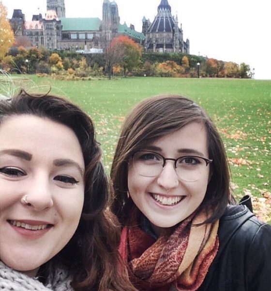 Kenya and Paloma taking a selfie in front of the Parliment buildings in Ottawa. The leaves are yellow and the two are wearing scarves for the chilly fall weather.