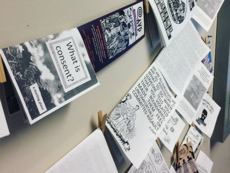 Photo of strands of zines hung up against a wall.