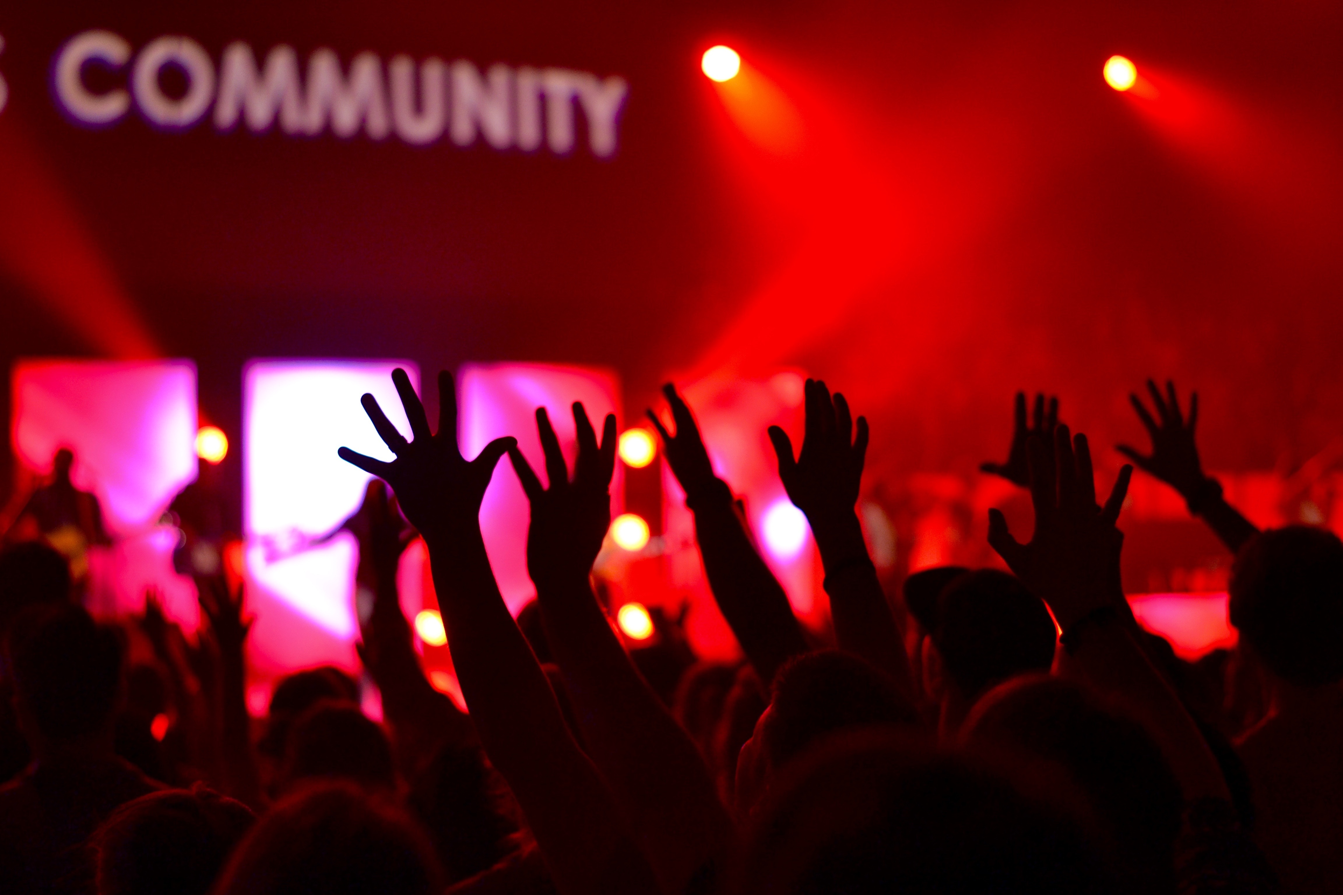 Image of crowd with outstretch hands, and the word "Community" on a sign in the background.
