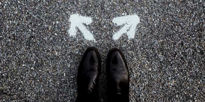 Making space for “maybe” Photo taken of a person's feet in black shoes. In front of the shoes are two arrows painted on the cement that are pointing left and right.