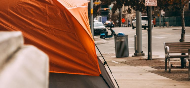 An open letter against policing at the Topaz Park homeless camp Image of an orange tent set up on a sidewalk, downtown in a city.